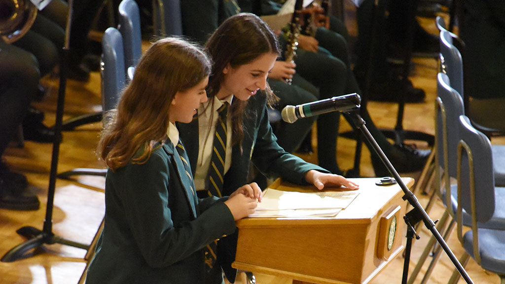 Two students standing at a podium with a microphone, ready to speak.