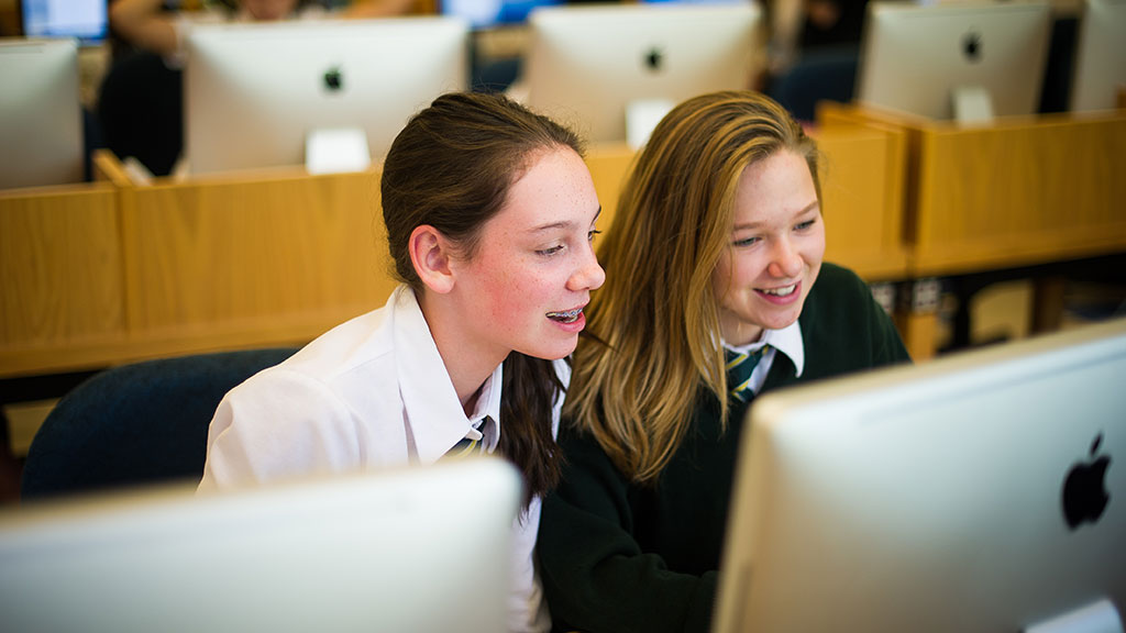 Two students looking at the monitor of a computer.