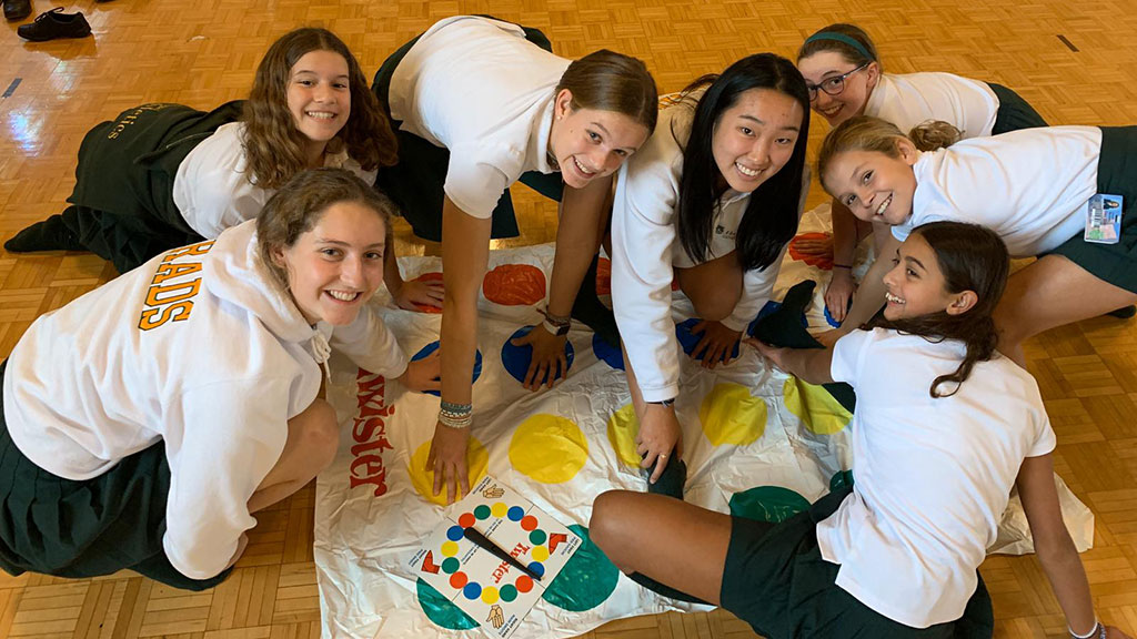 A group of Middle School students and Grads play Twister in the Brenda Robson Hall.