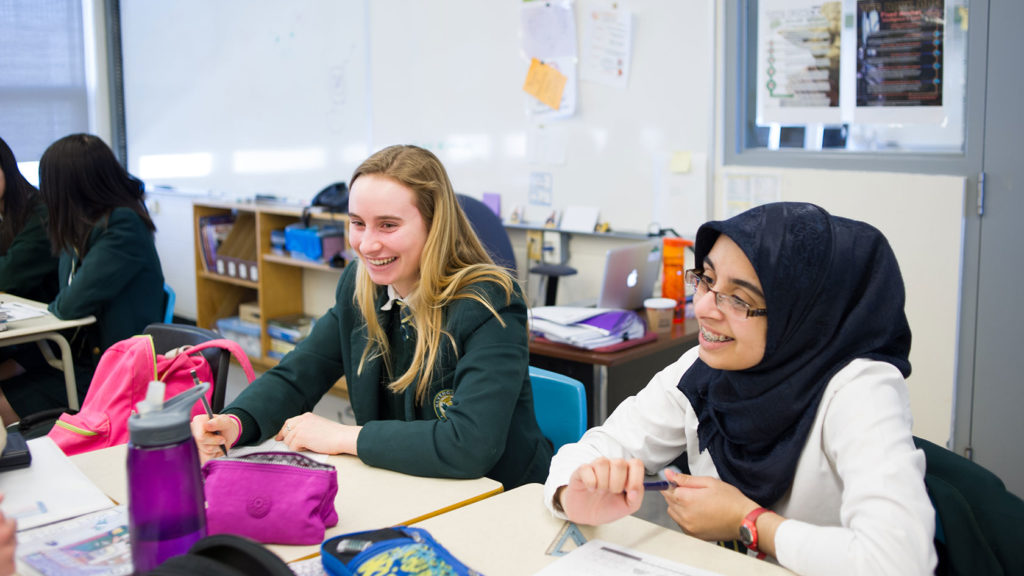 Two students smiling and actively engaged in class.