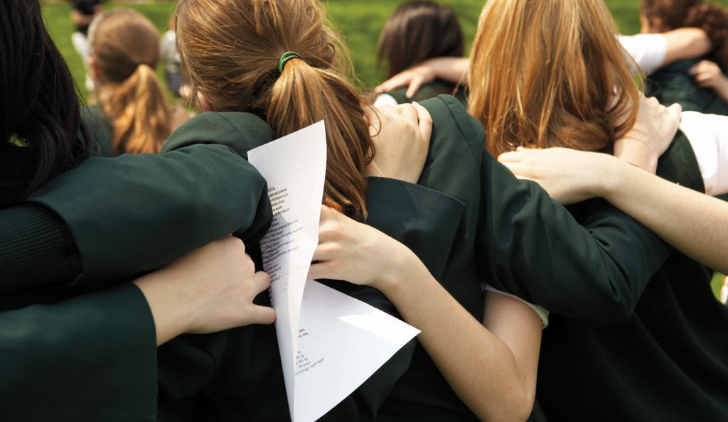 View from behind of friends in Havergal green uniforms locked arm in arm.