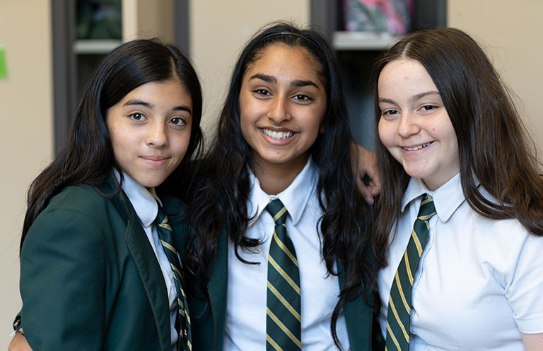Three Middle School students standing together and smiling