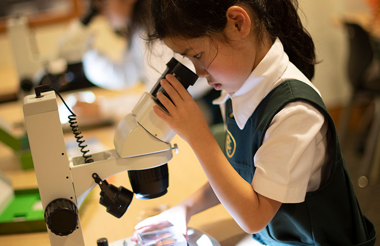 Junior School student looking into a microscope