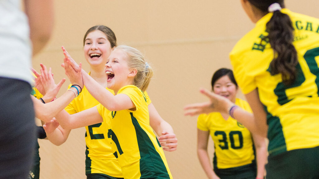 Students high five at U12 Volleyball game.