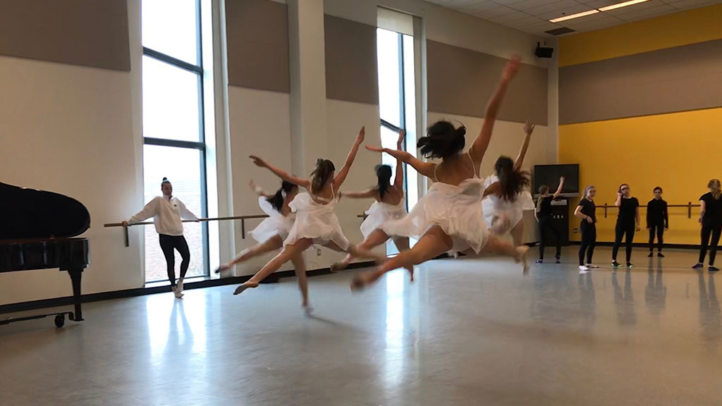 Students practise their dance routine in a dance studio.