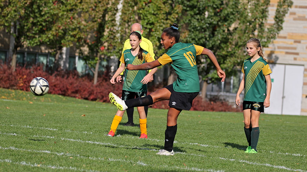 A student ready to kick the ball in a U14 Soccer game.