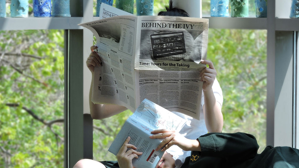 Two students in the library, one reading Behind the Ivy, the other reading a book.