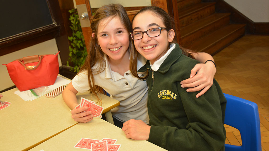 Two students posing together with their hands of playing cards.