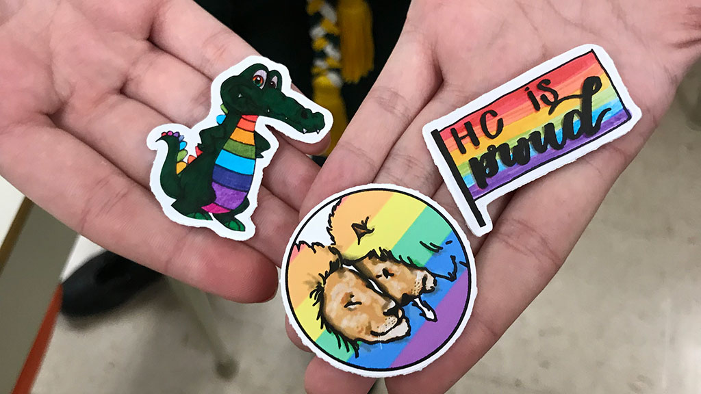 Three Havergal Pride stickers displayed on a pair of open hands.