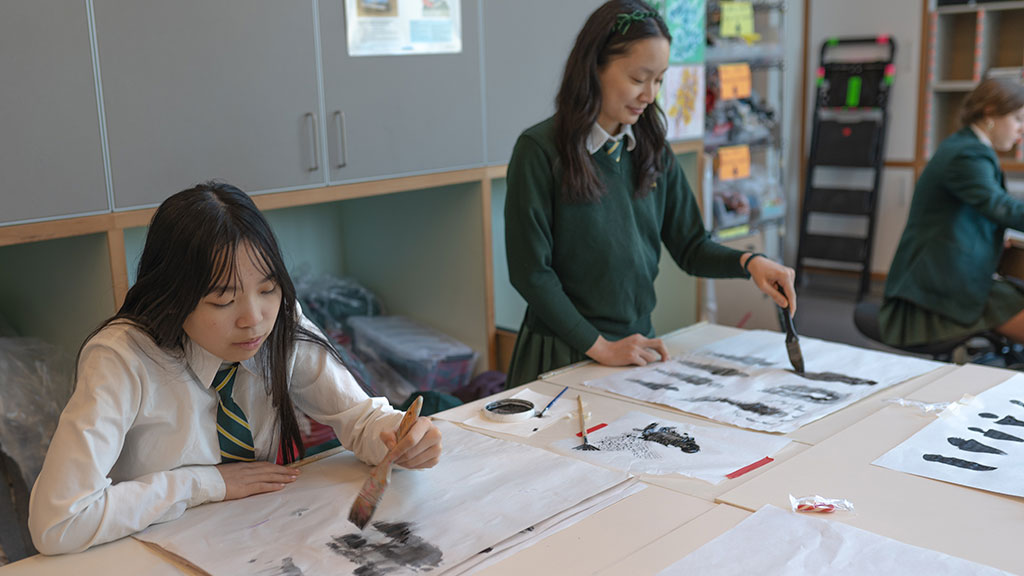Two students paint in an art classroom.