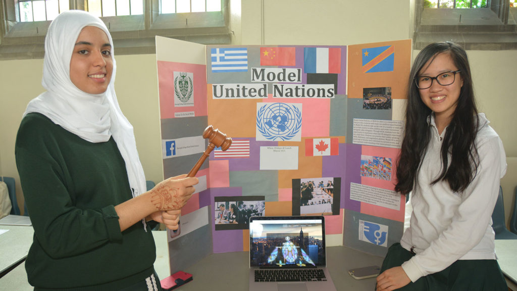 Two students stand beside a poster for the Model United Nations club.