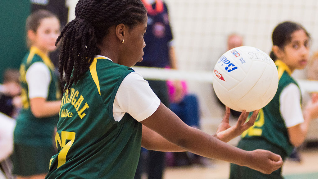 A Junior School student prepares to serve a volleyball.