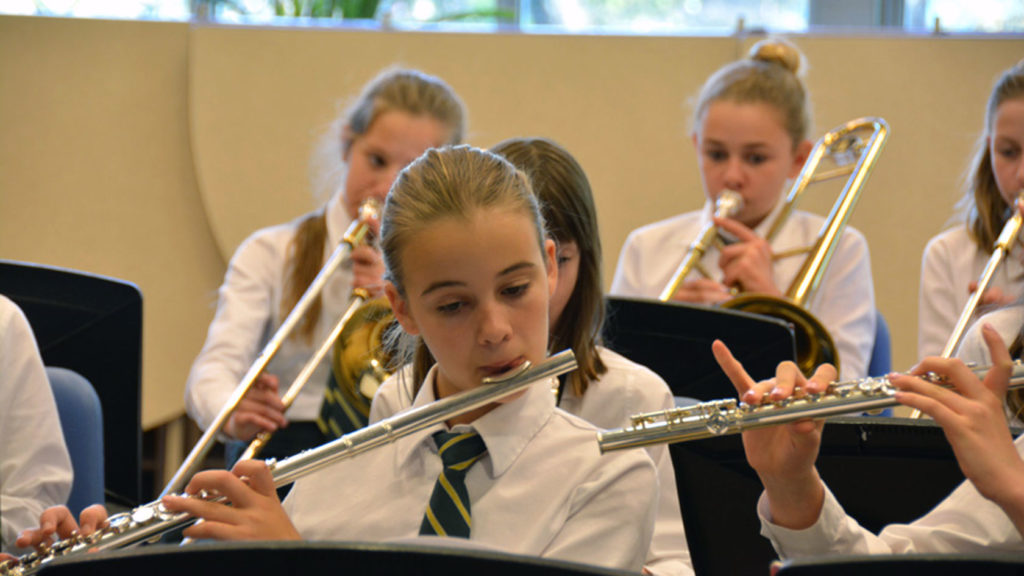 A student playing the flute in a band.