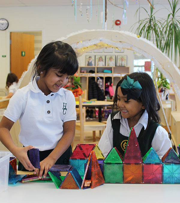 Two Kindergarden students play with coloured blocks.