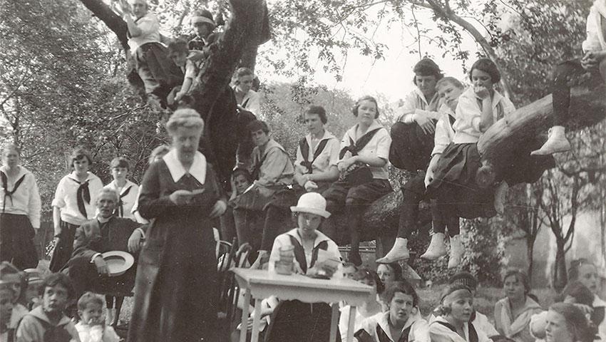 Ellen Knox reads to children who are sitting on and around a tree.