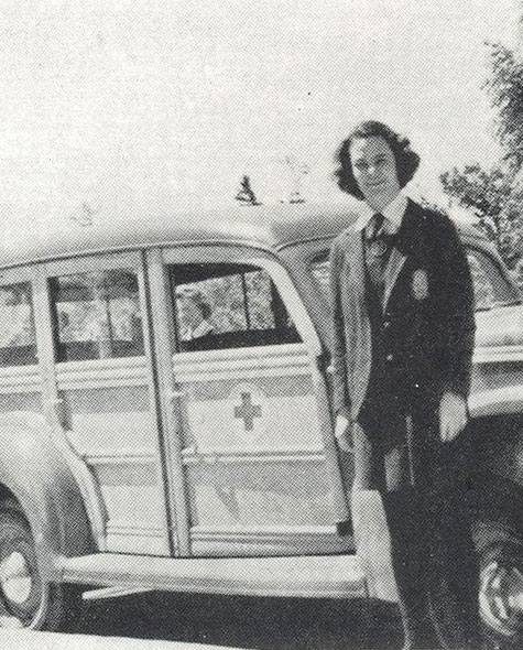Black and white photo of a student posing beside an ambulance in 1942.