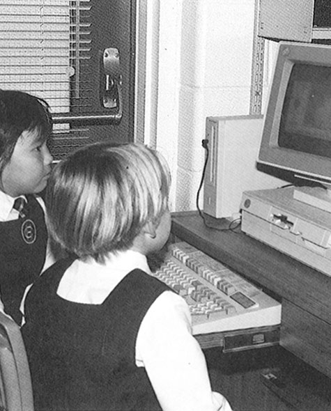 Black and white photo of two young students looking at a computer in 1981.