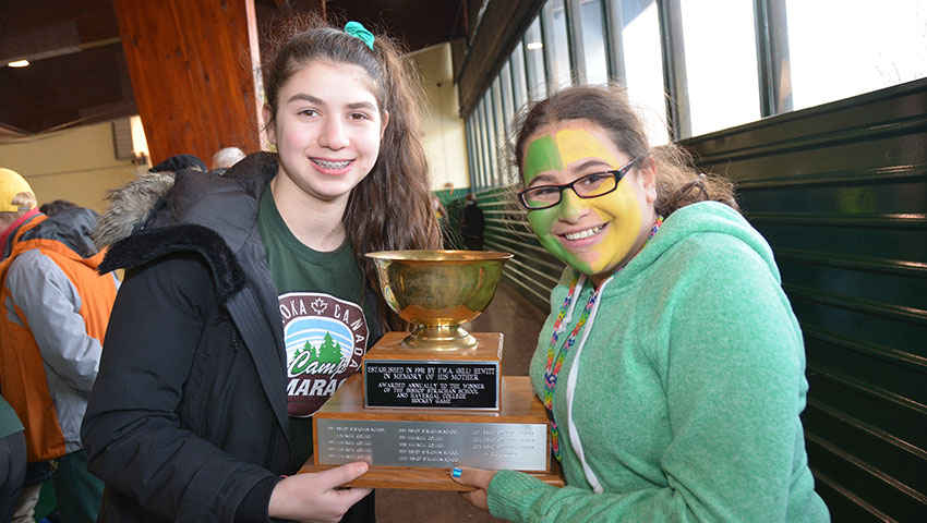 Two students dressed in spirit wear holding the Hewitt Cup.