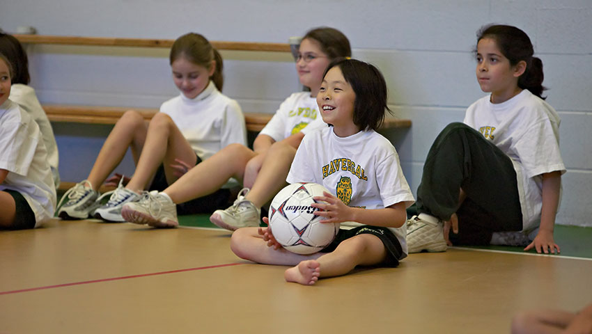 Junior School students sit on the gym floor.