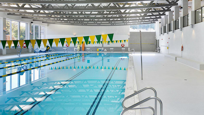 Indoor pool with green and gold flags hanging above the lanes.