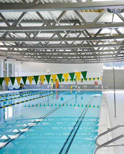 View of the indoor pool with green and gold banners hanging above the lanes.