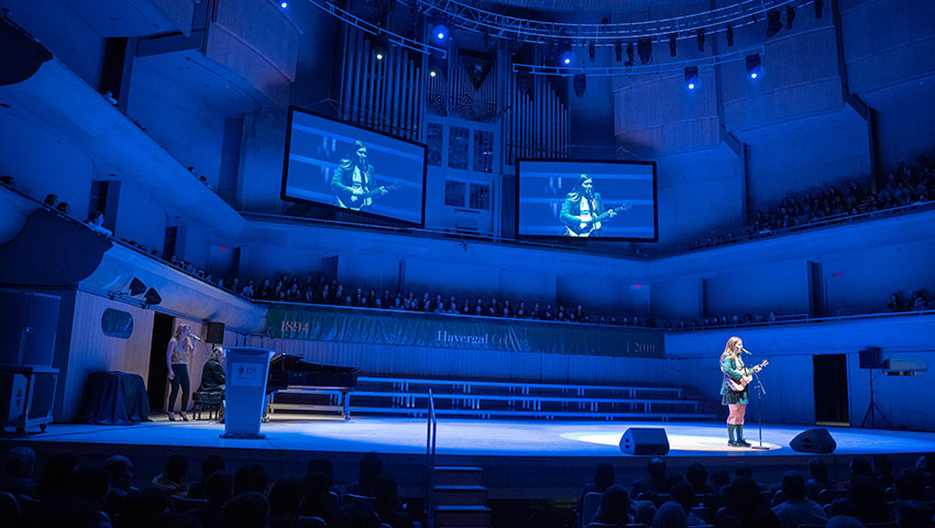 A student plays guitar on the stage at Roy Thomson Hall.