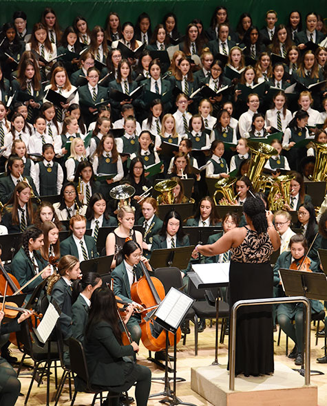 Students sing and perform in a band on a stage.