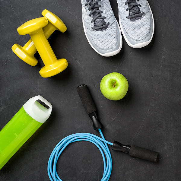 Image of running shoes, skipping rope, water bottle, apple and hand weights representing "Fitness"