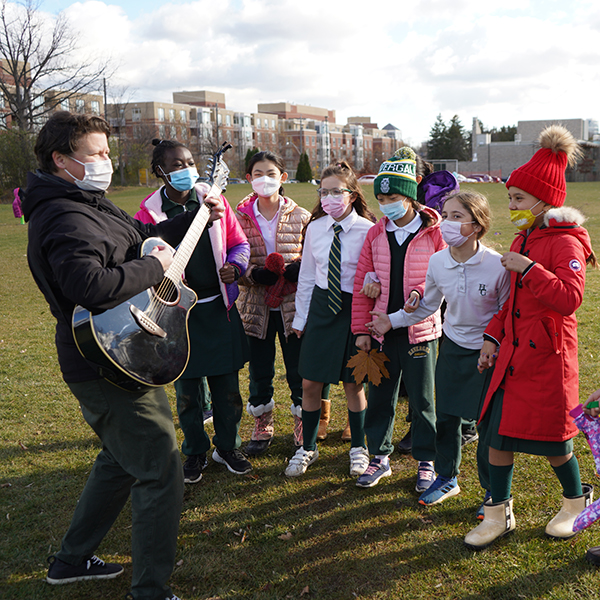 teacher playing guitar with students singing along