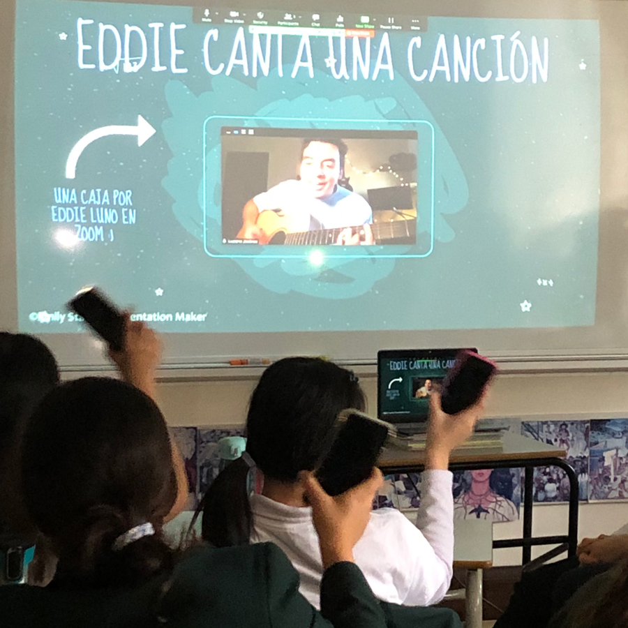 Students holding up phones while Eddie Luno performs on screen.