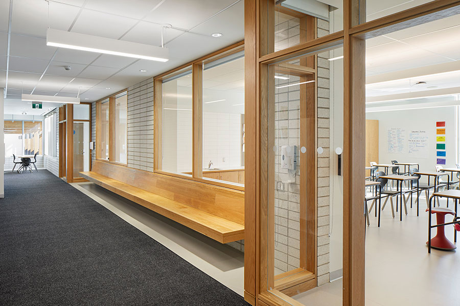 A school hallway with windows that look in to the adjoining classrooms.