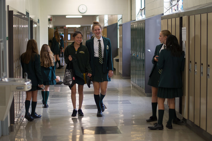 Two students walk down a school hallway.