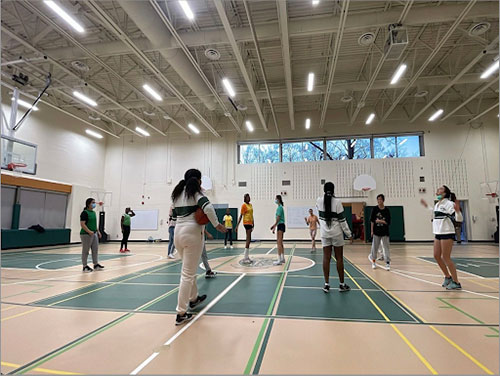 Boarders play basketball in a gym.