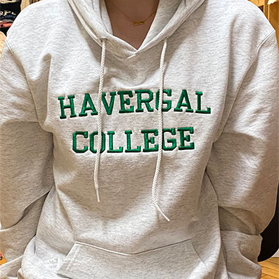 A Boarder wearing a Heather grey hoodie with "Havergal College" on the front in green block letters.