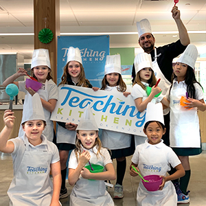 Junior School students wearing chef uniforms participating in the Teaching Kitchen.