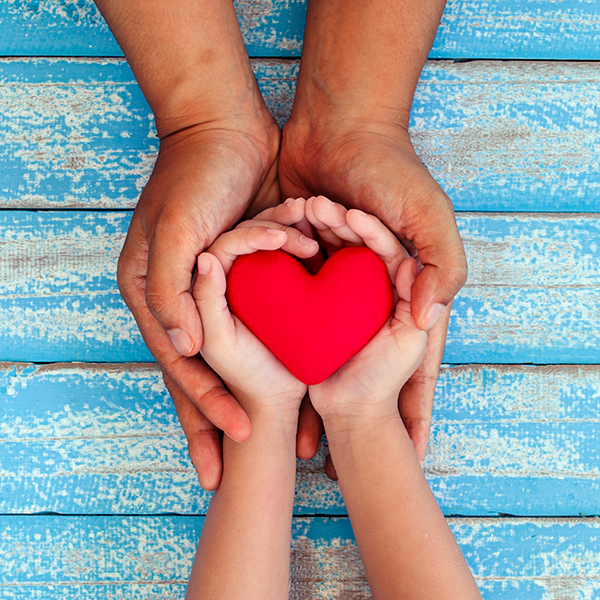 Adult and child hands holding a heart