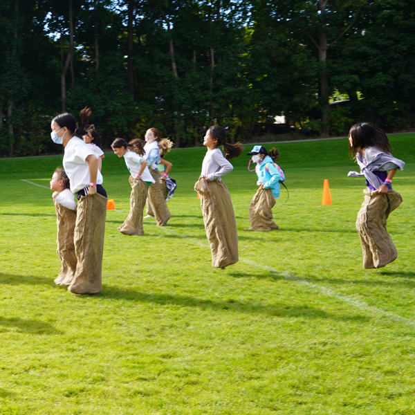 Junior School students doing a potato sack race during Celebration Saturday 2022.