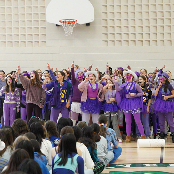 Grade 8 students wearing purple and performing a cheer.