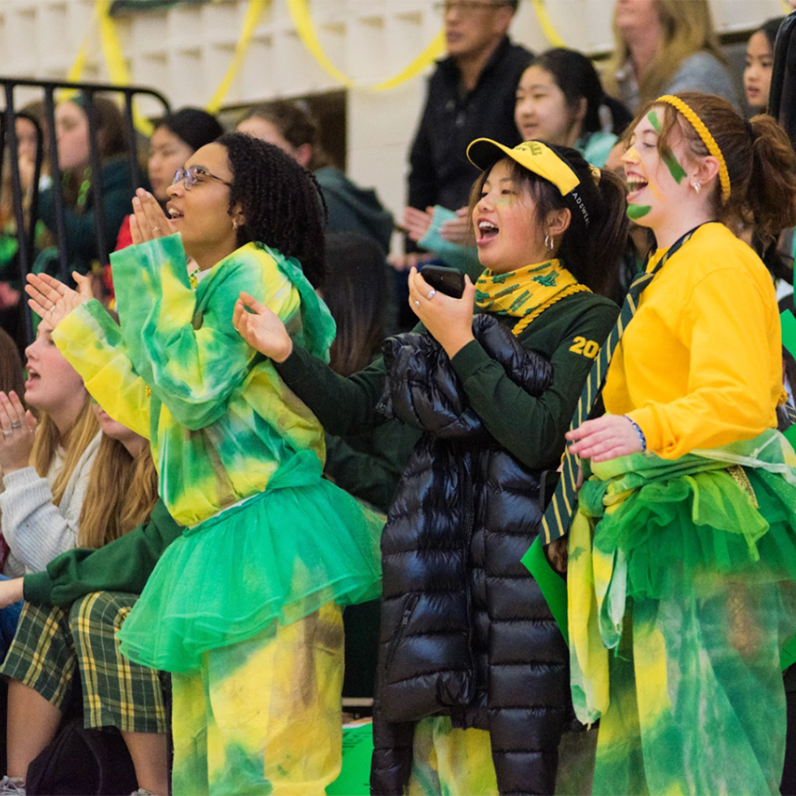 Students wearing green and gold spirit wear cheering.