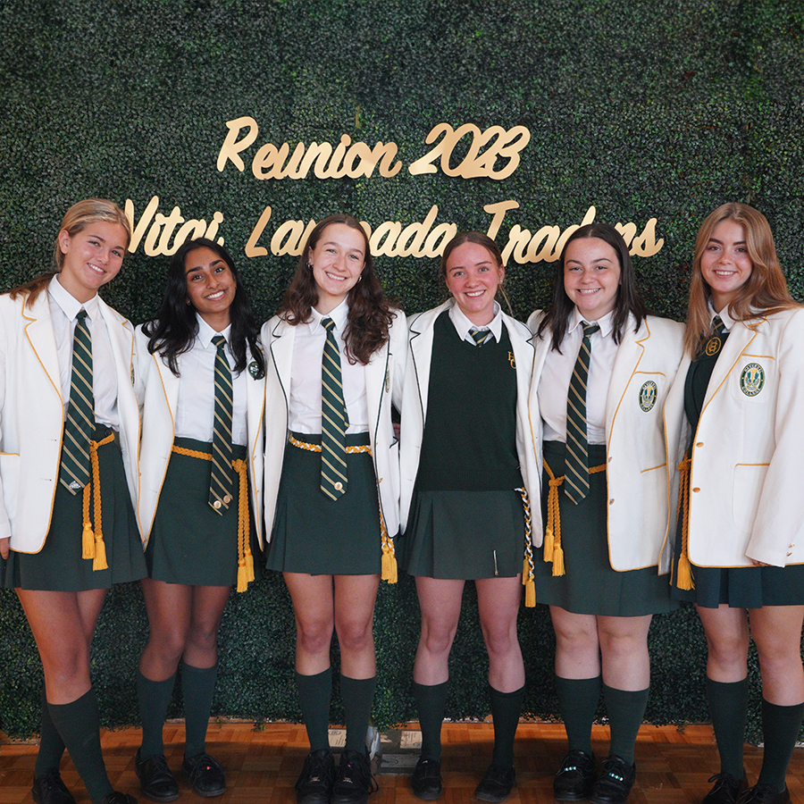 Grade 12 students standing at a green backdrop that says "Reunion 2023"