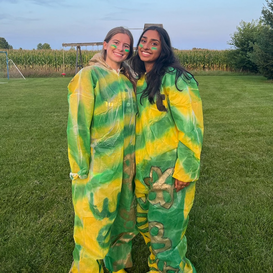 The Admissions Prefects wearing bold green and gold outfits standing in a field.