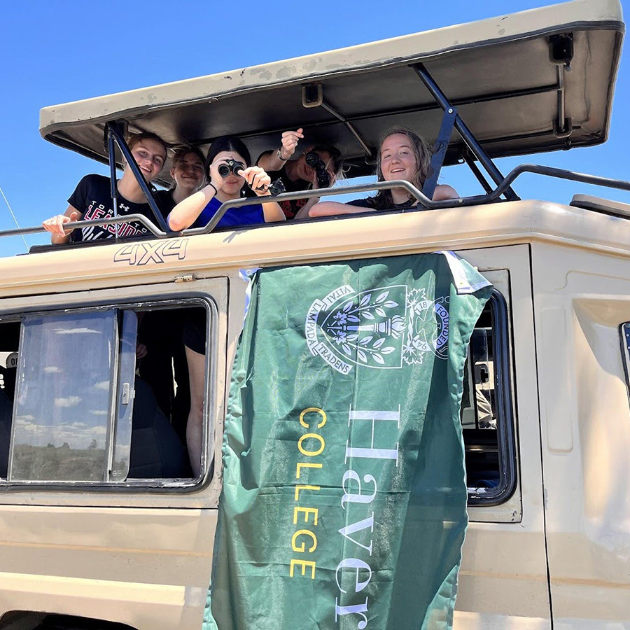 Students on safari with binoculars and the Havergal College flag.