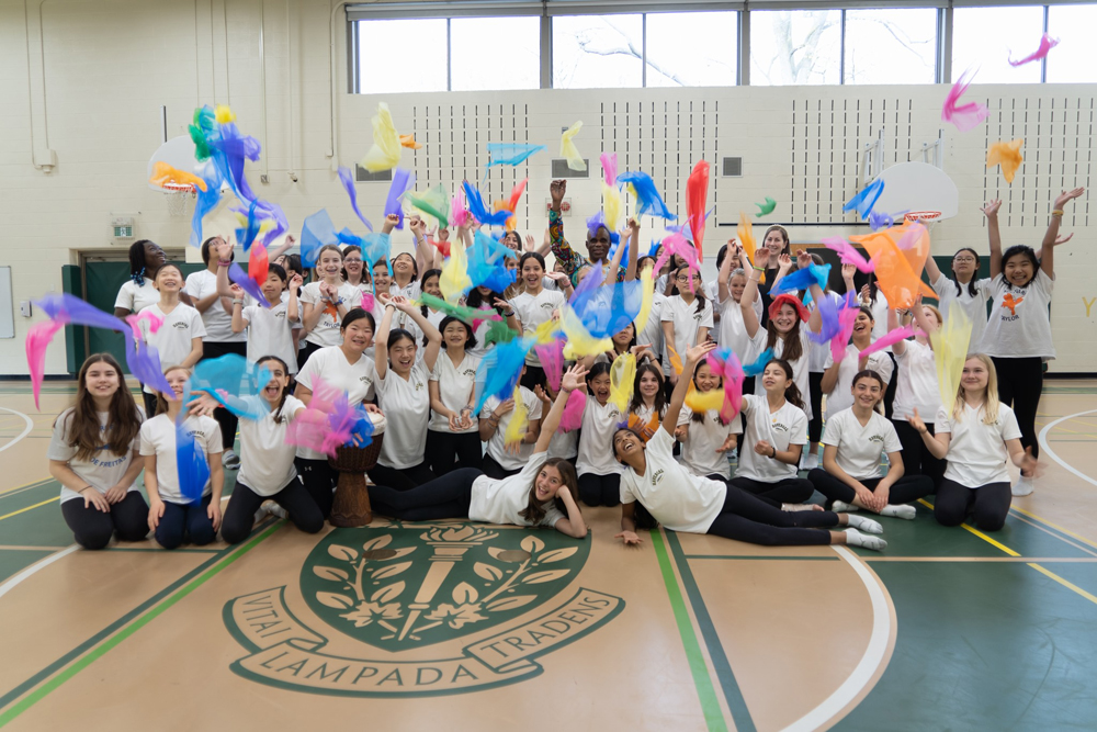 Students holding up colourful scarves after a dance performance.