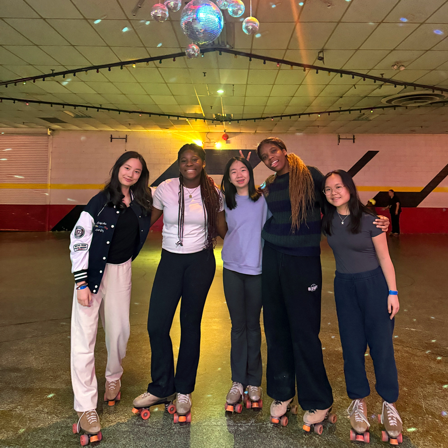 Boarding students wearing rollerskates under a disco ball.