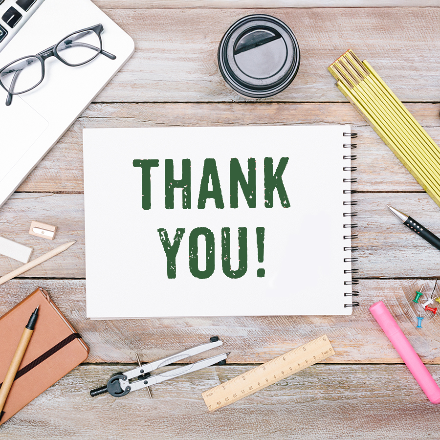 "Thank you!" written on a notebook with other office tools on the table