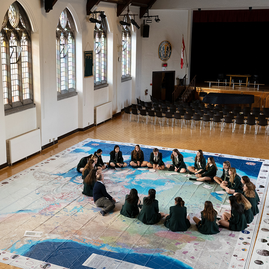 Students sitting on a giant map of the oceans.