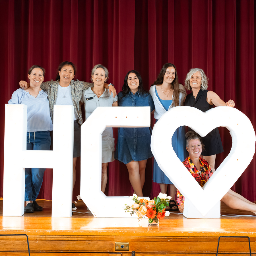 Faculty standing around a giant "HC" sign with a heart.