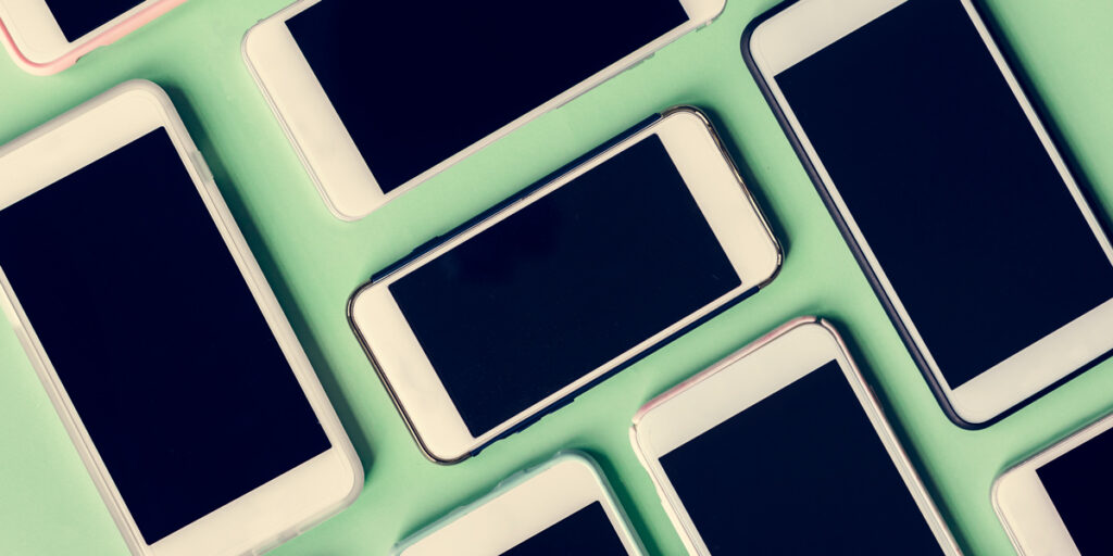 Stock image of phones on a green table.